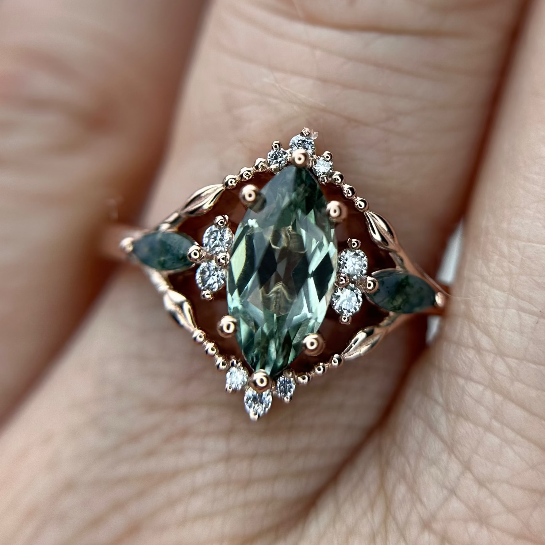 Rose Gold Ring with a green sapphire gemstone on a finger