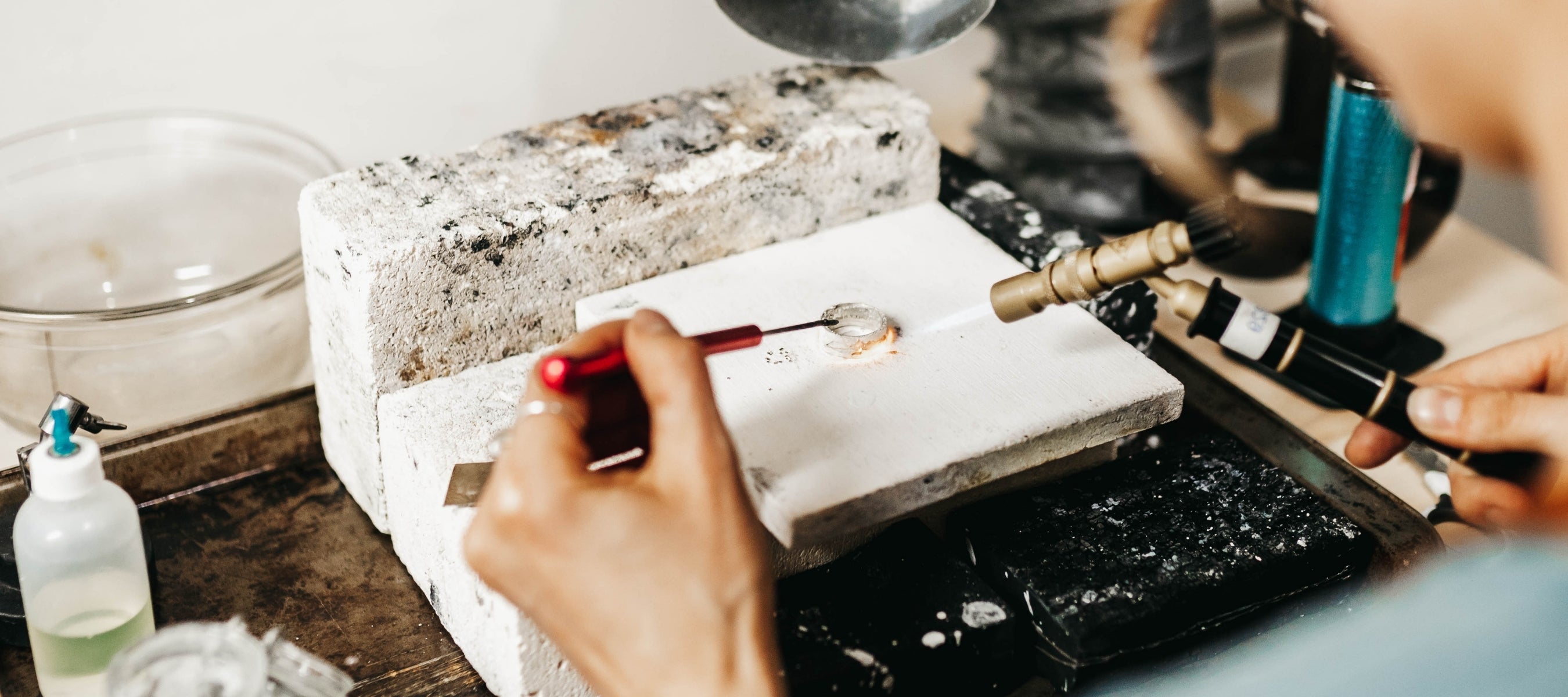 owner of Scenic Route Jewellery, Brittani, working in her studio with a torch creating a men's mountain wedding ring.