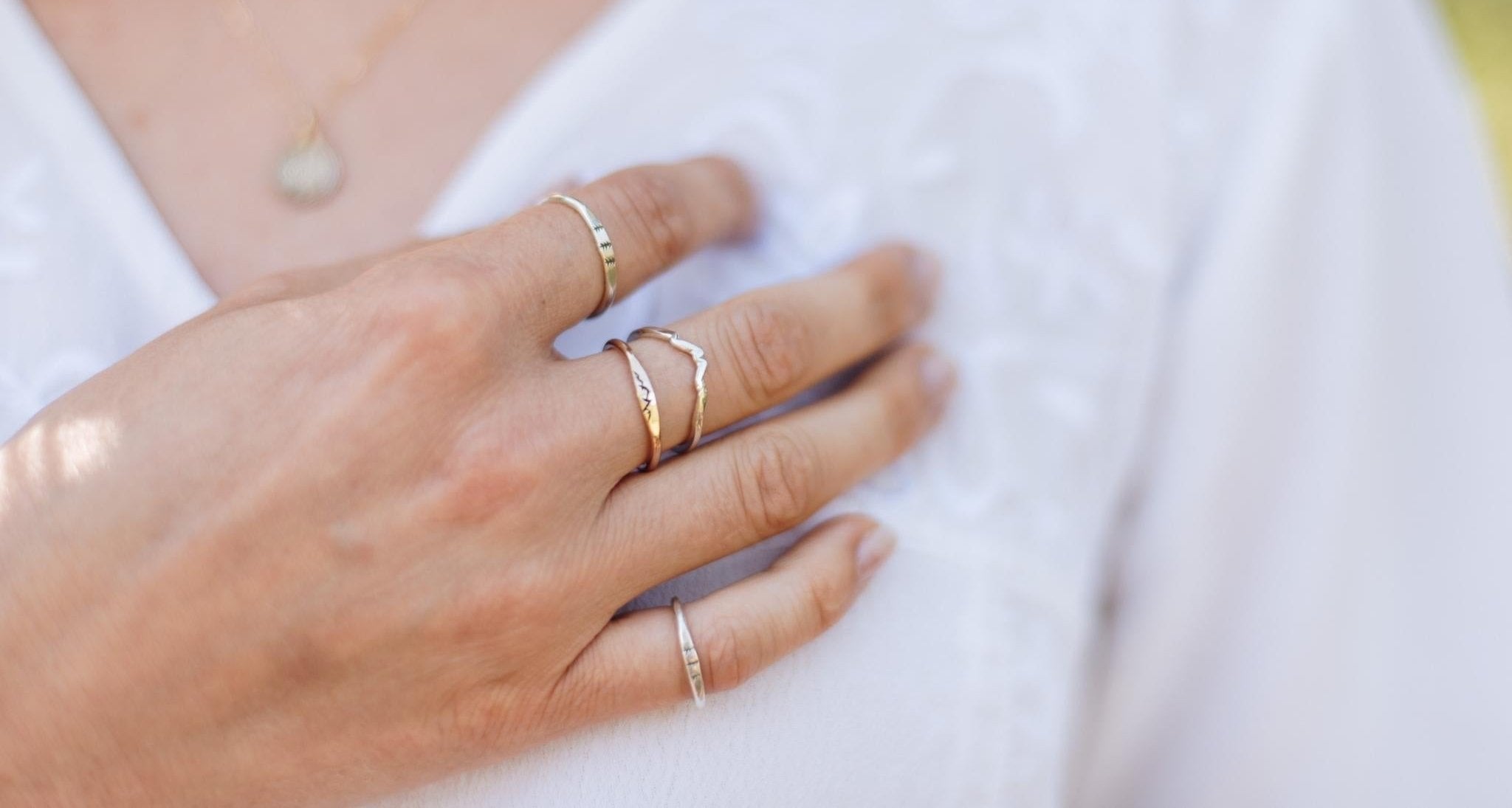 Woman's hand with multiple silver and gold nature inspired rings on each finger.