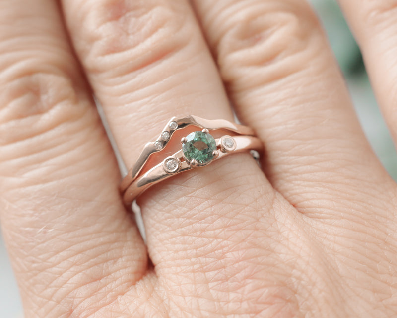 rose gold mountain band ring with 3 lab grown diamonds paired with a custom teal sapphire engagement ring.