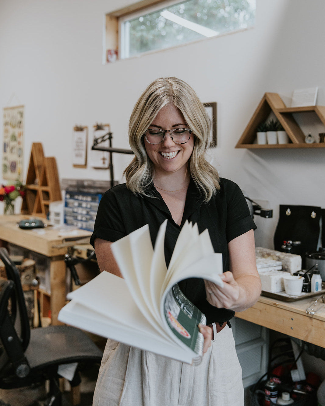 goldsmith artist holding a sketchbook in a workshop setting
