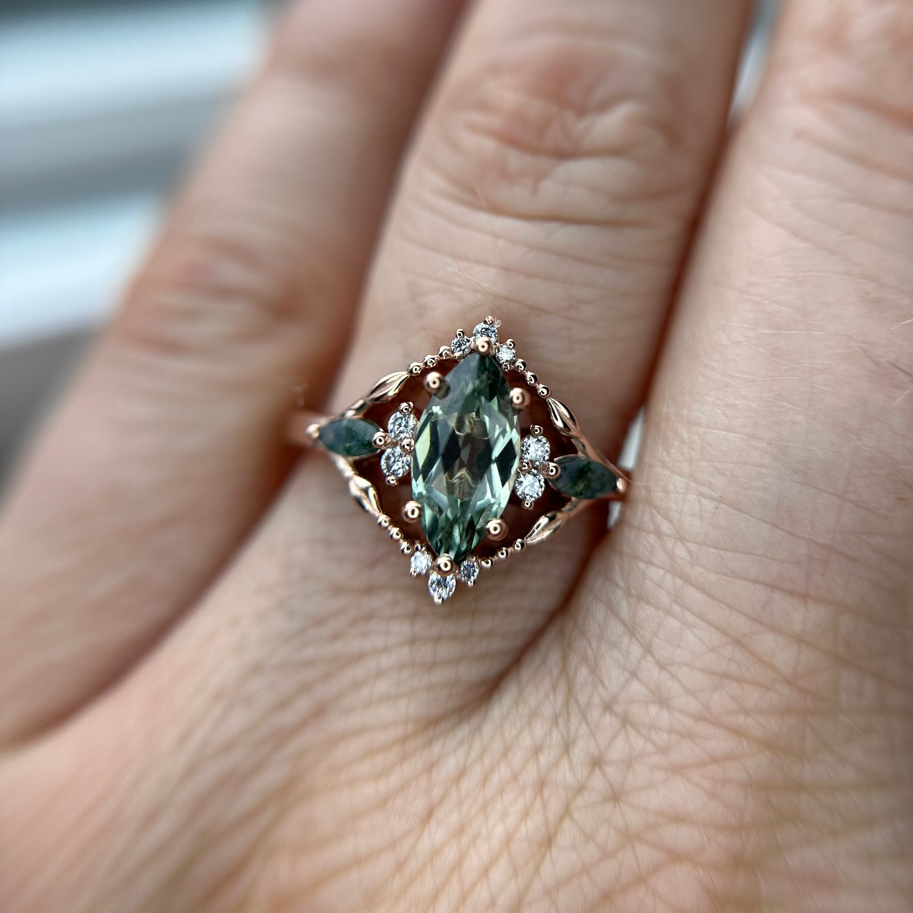 Rose Gold Ring with a green sapphire gemstone on a finger
