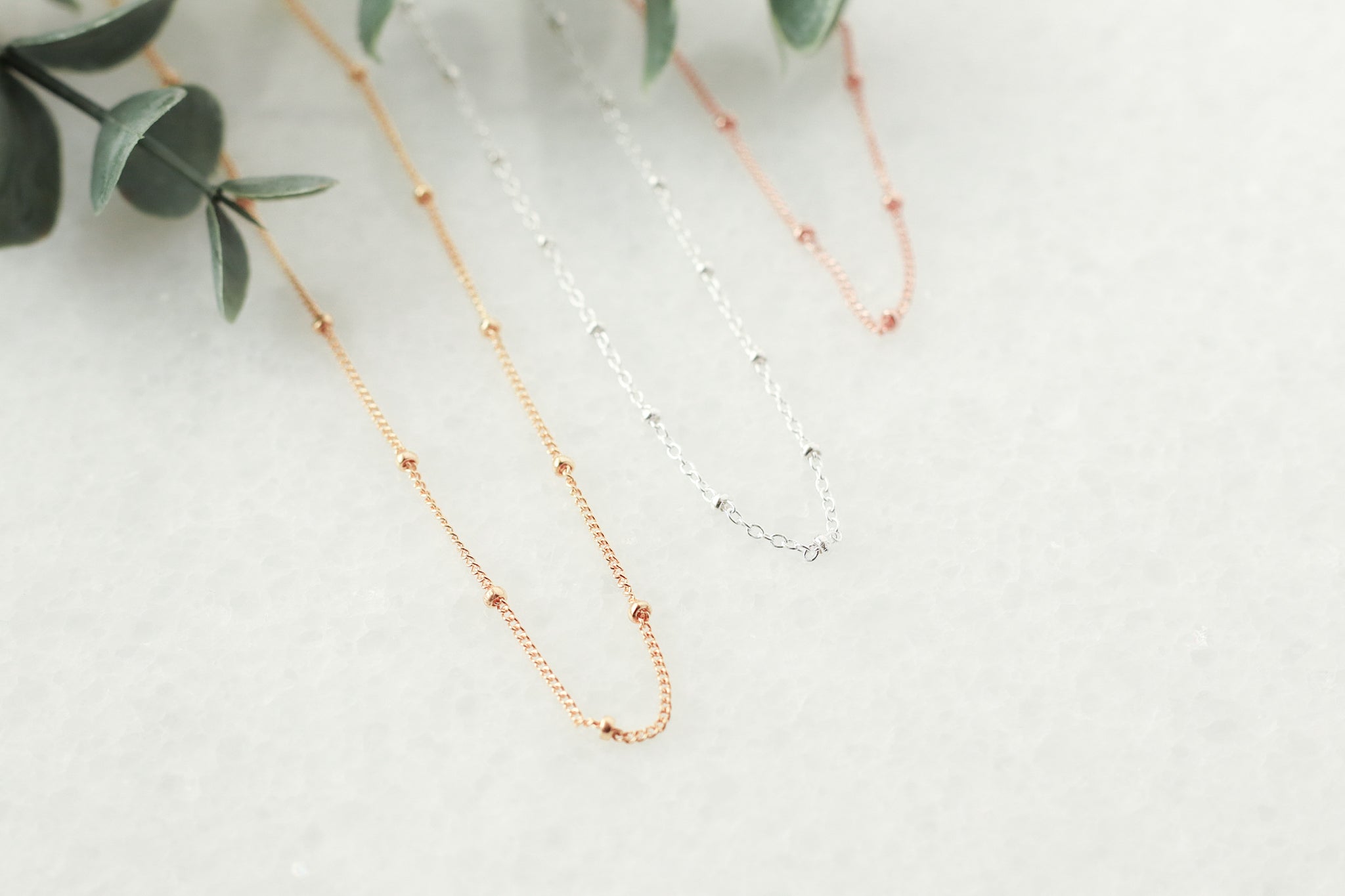 rose, yellow and silver beaded chains on quartz background