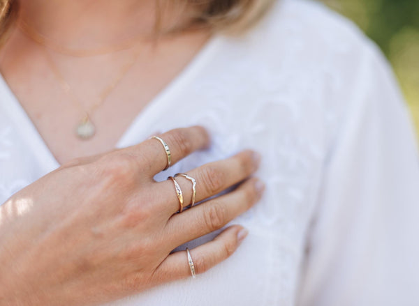 Woman's hand with multiple silver and gold nature inspired rings on each finger.