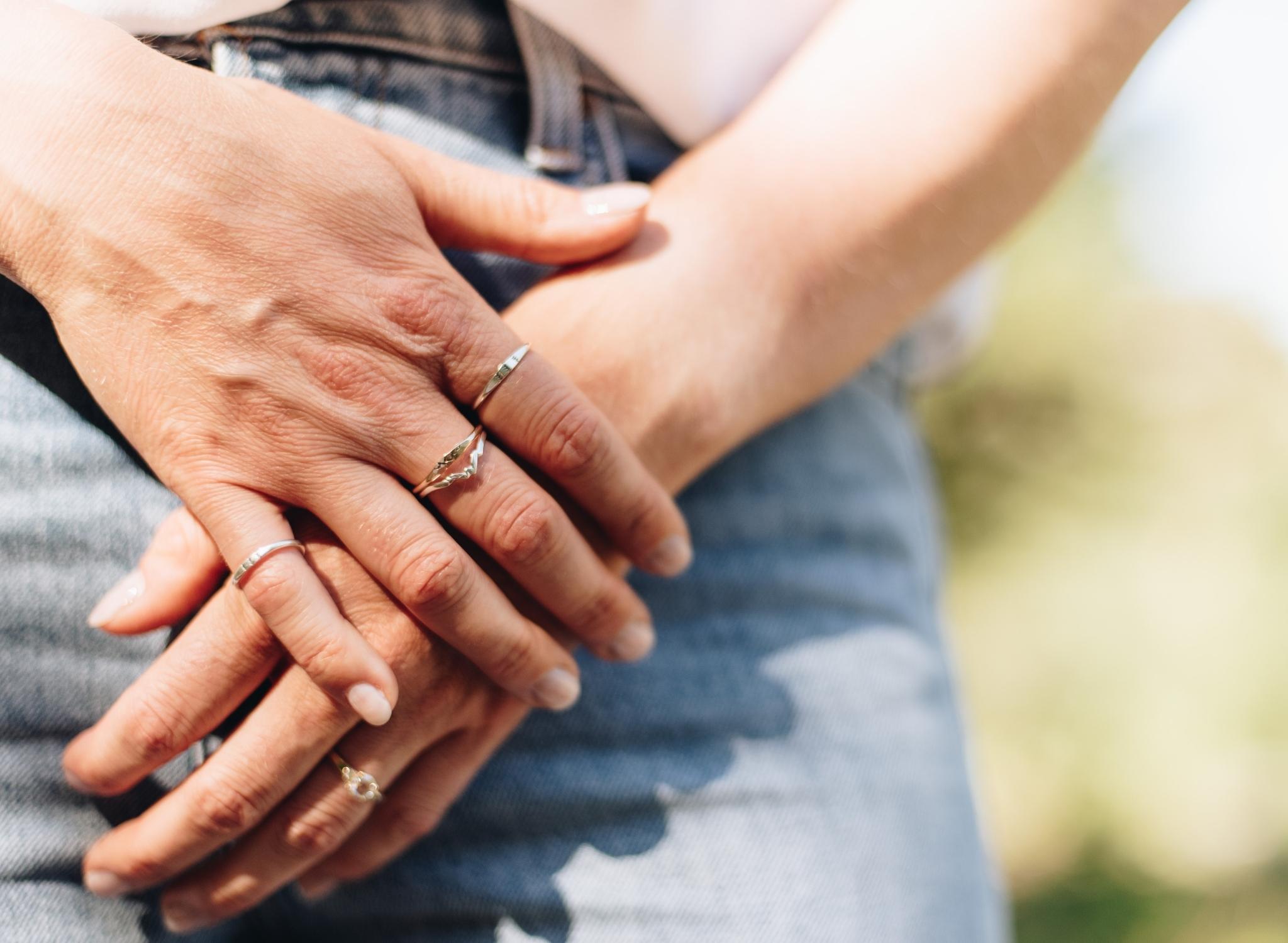 Woman's hand with multiple silver and gold nature inspired rings on each finger.