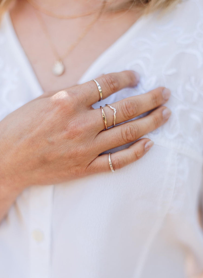 Woman's hand with multiple silver and gold nature inspired rings on each finger.