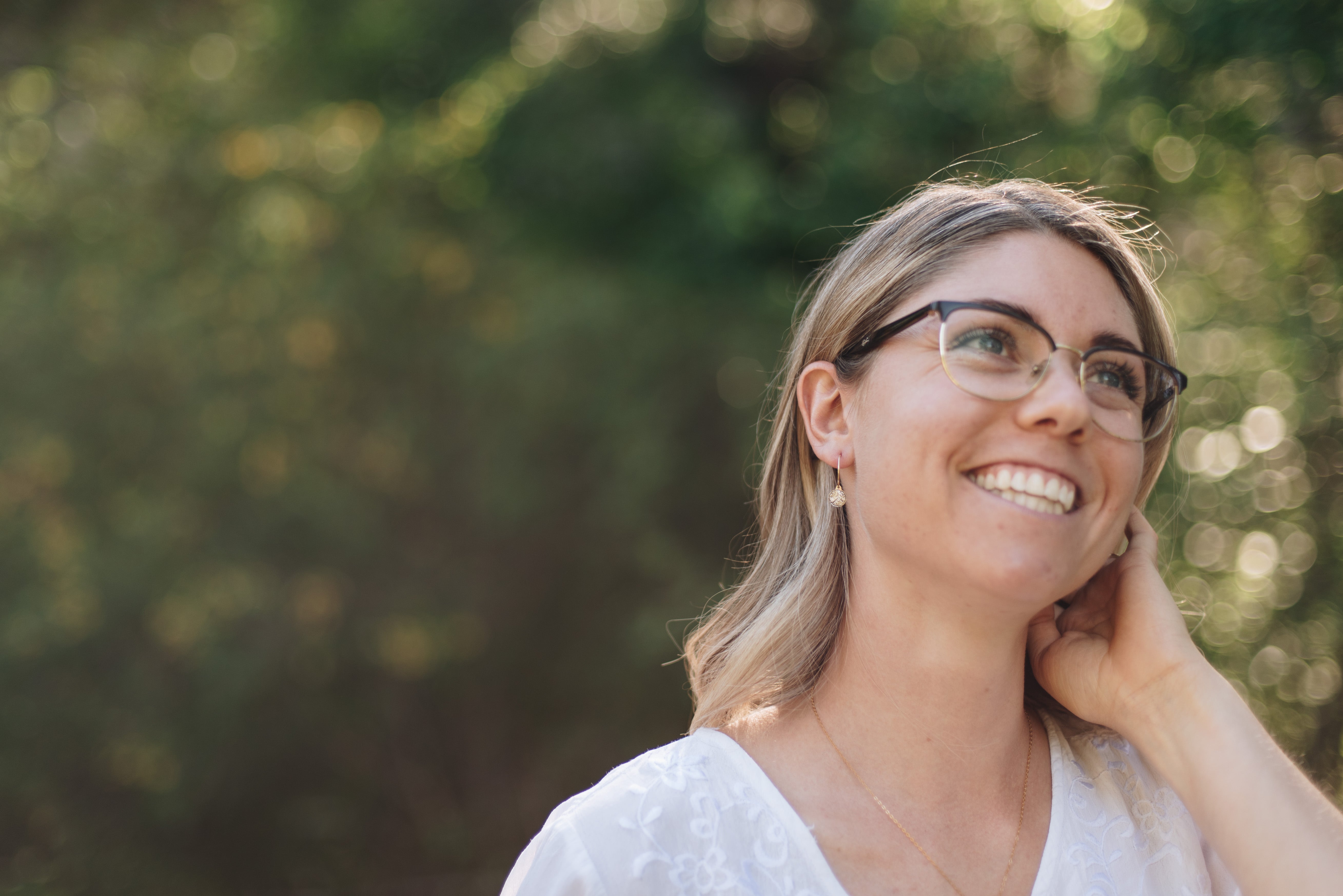 Woman in a forest wearing gold wire hoops with wood slice charms.