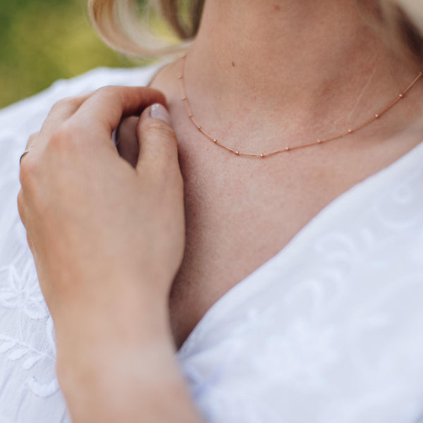 Delicate rose gold beaded chain on a women with blonde hair