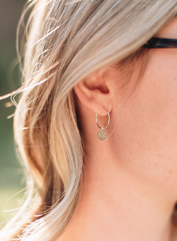 Silver hoop earrings with tree slice charms.
